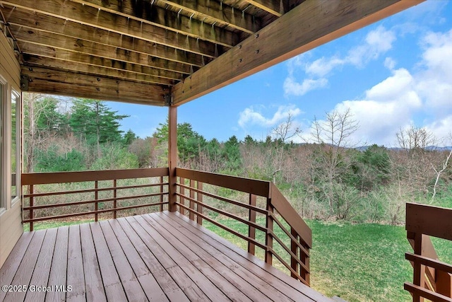 wooden terrace featuring a lawn and a wooded view