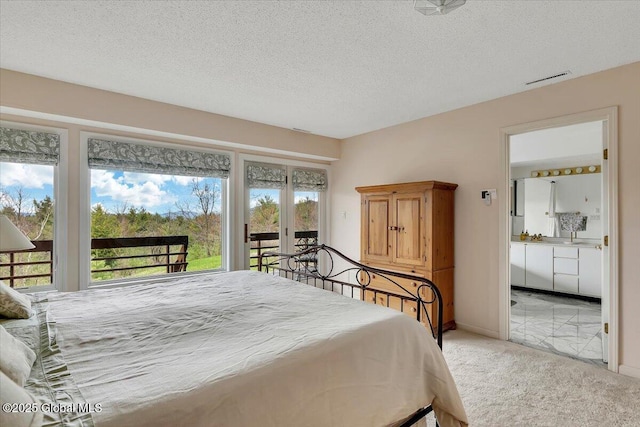 bedroom featuring a textured ceiling, connected bathroom, light carpet, access to exterior, and visible vents