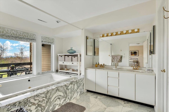 bathroom with double vanity, a garden tub, marble finish floor, and a sink