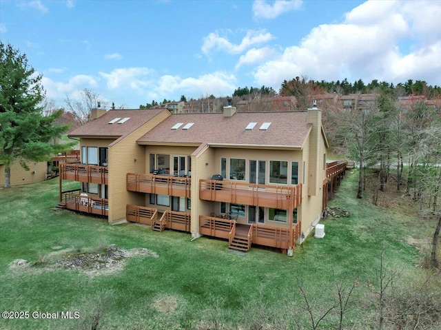 back of property with a chimney, a deck, a balcony, and a lawn