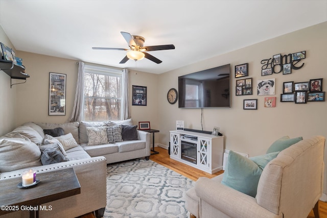 living area with baseboards, a ceiling fan, and wood finished floors