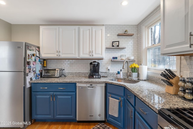 kitchen with a sink, blue cabinetry, backsplash, and stainless steel appliances