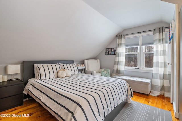 bedroom with wood finished floors and lofted ceiling
