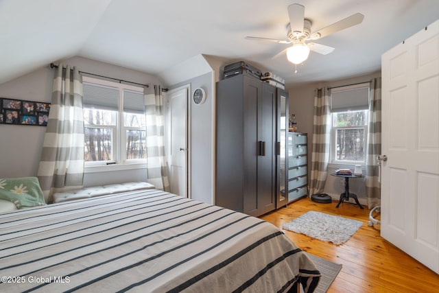 bedroom with ceiling fan, vaulted ceiling, and light wood-type flooring
