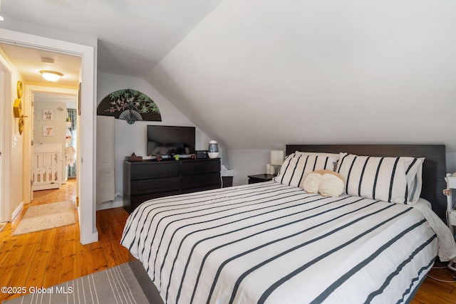 bedroom featuring light wood-style floors and vaulted ceiling