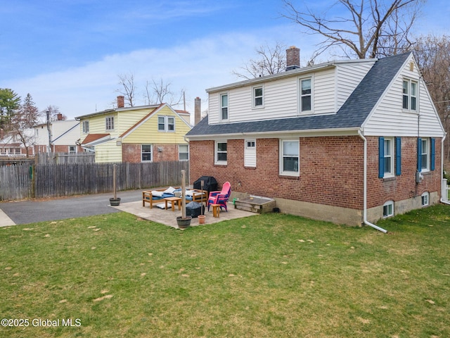 back of property with brick siding, a lawn, fence, and a patio