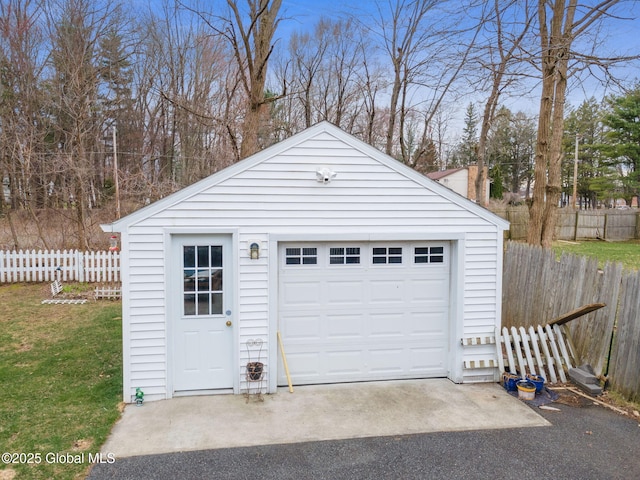 detached garage featuring fence and driveway