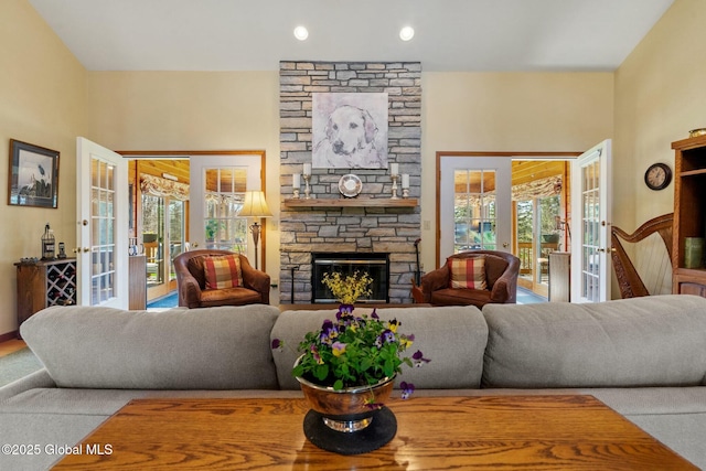 living area with recessed lighting, a stone fireplace, and french doors