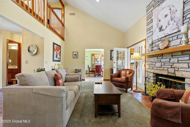 tiled living room featuring high vaulted ceiling, a stone fireplace, and visible vents