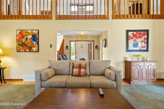 living area with baseboards, visible vents, and a towering ceiling