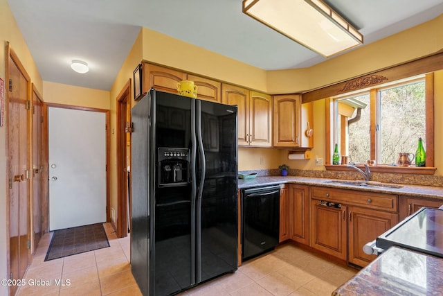 kitchen with light tile patterned floors, brown cabinetry, a sink, and black appliances