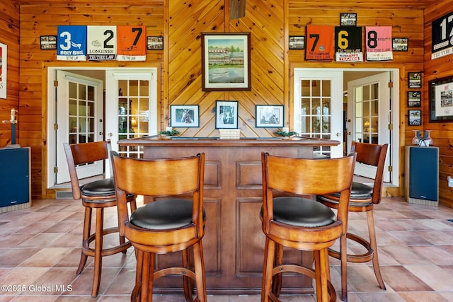 bar featuring french doors, wood walls, and a bar