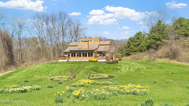 back of property featuring roof with shingles, a wooden deck, and a yard