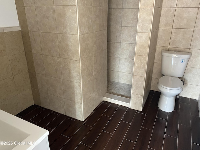 bathroom with toilet, tile walls, and wood tiled floor
