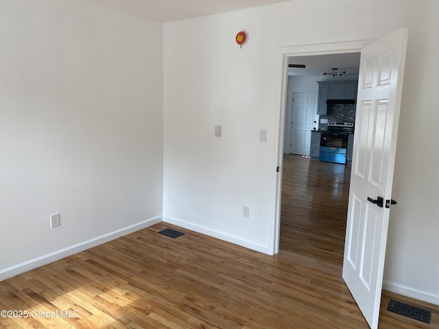 empty room with baseboards, visible vents, and wood finished floors