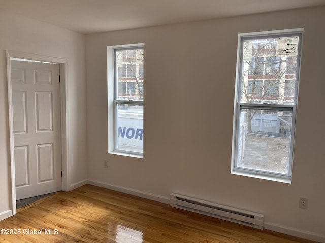 unfurnished room with baseboards, wood finished floors, and baseboard heating
