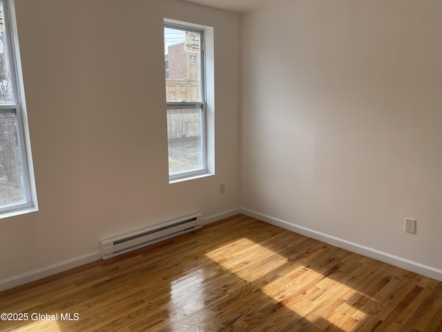 empty room with a baseboard radiator, baseboards, and wood finished floors