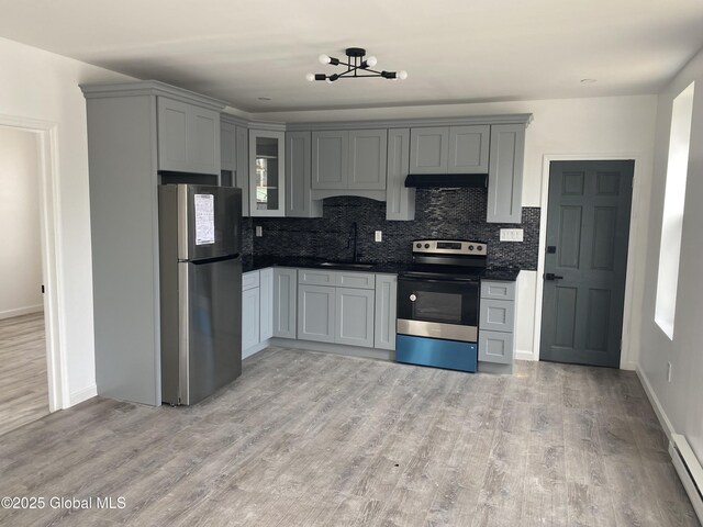 kitchen featuring gray cabinets, a sink, appliances with stainless steel finishes, and light wood-style floors