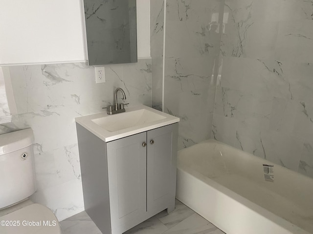 full bath featuring marble finish floor, a washtub, toilet, and vanity