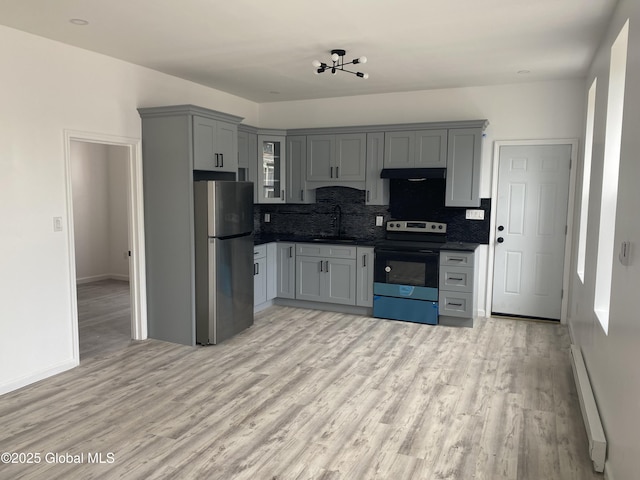kitchen with a sink, freestanding refrigerator, under cabinet range hood, range with electric cooktop, and a baseboard heating unit