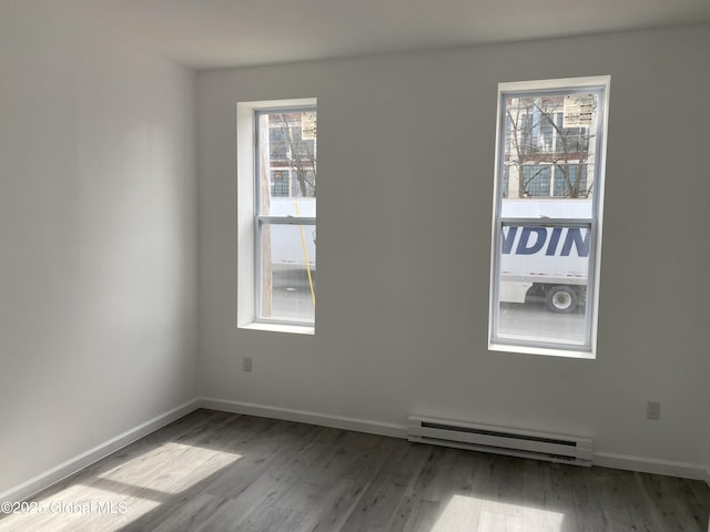 unfurnished room with baseboards, wood finished floors, and a baseboard radiator