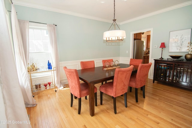 dining area with ornamental molding, light wood-style floors, a chandelier, and wainscoting
