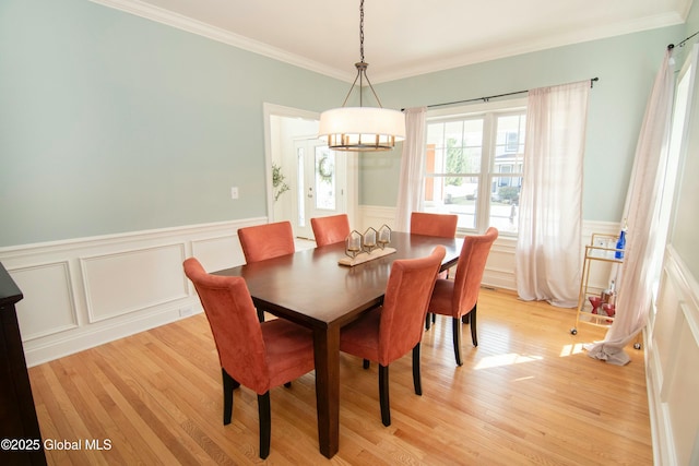 dining space featuring a wainscoted wall, light wood-style floors, ornamental molding, and a chandelier