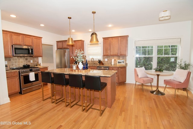 kitchen featuring brown cabinets, light wood-type flooring, and appliances with stainless steel finishes