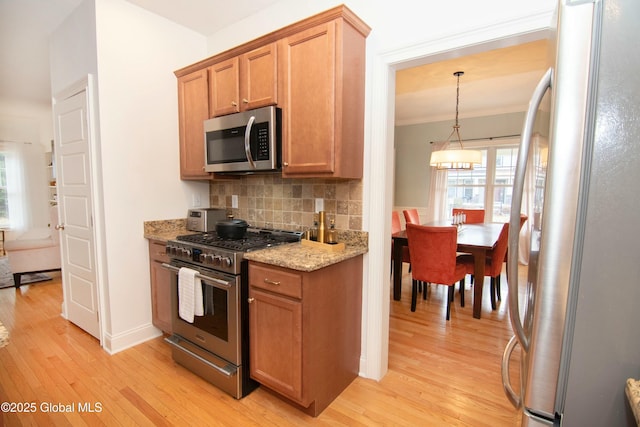 kitchen featuring light wood finished floors, backsplash, appliances with stainless steel finishes, and light stone counters