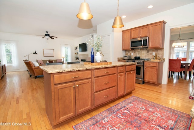 kitchen featuring a kitchen island, a ceiling fan, tasteful backsplash, appliances with stainless steel finishes, and plenty of natural light