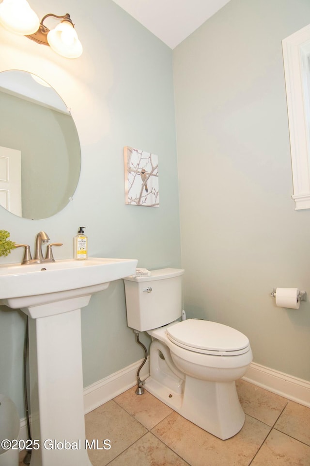 bathroom with baseboards, toilet, and tile patterned flooring