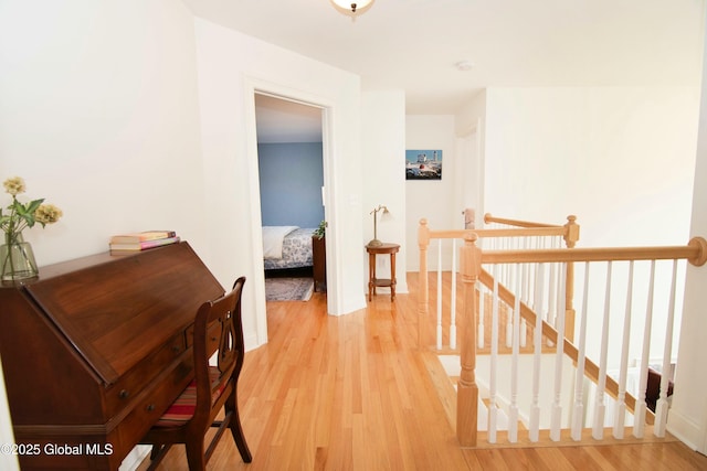 corridor featuring baseboards, an upstairs landing, and light wood-style flooring