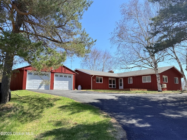 single story home featuring board and batten siding, an attached garage, a chimney, and aphalt driveway