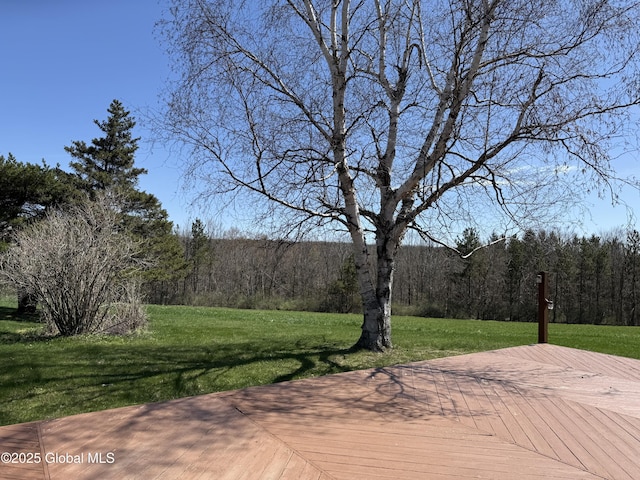 surrounding community featuring a yard, a view of trees, and a wooden deck