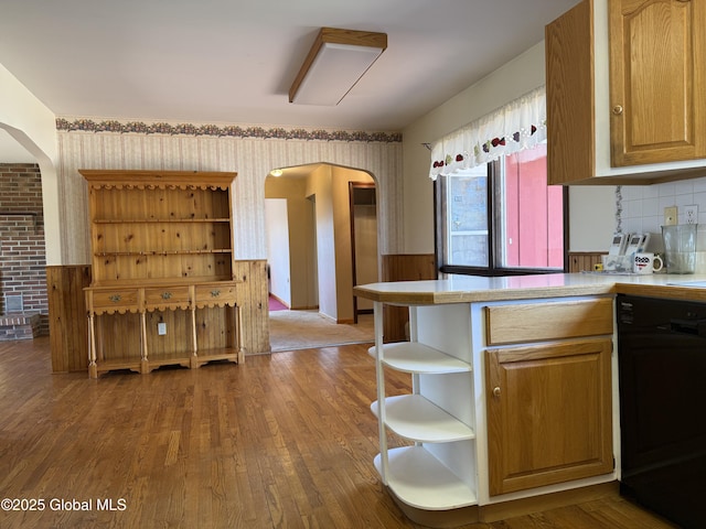 kitchen featuring open shelves, wood finished floors, dishwashing machine, wallpapered walls, and arched walkways