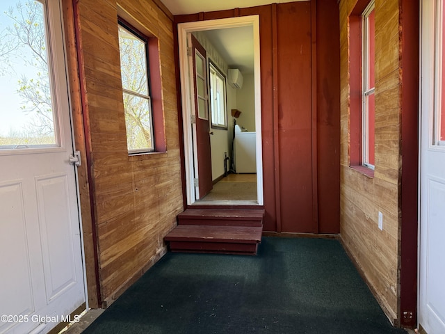 hallway with a healthy amount of sunlight, carpet flooring, wood walls, and an AC wall unit