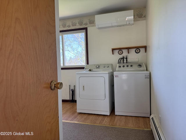 laundry room featuring laundry area, wood finished floors, a baseboard radiator, a wall mounted AC, and washing machine and dryer