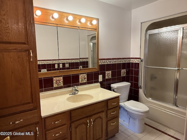full bathroom with vanity, shower / bath combination with glass door, tile walls, a wainscoted wall, and tile patterned floors