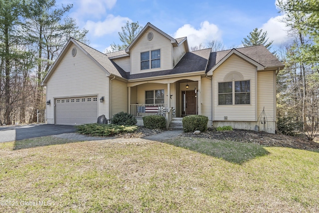 traditional-style house featuring a front lawn, aphalt driveway, a shingled roof, covered porch, and an attached garage