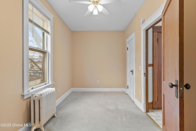 bedroom with a ceiling fan, radiator, baseboards, and light colored carpet