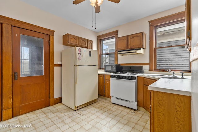 kitchen with under cabinet range hood, light countertops, a ceiling fan, and white appliances
