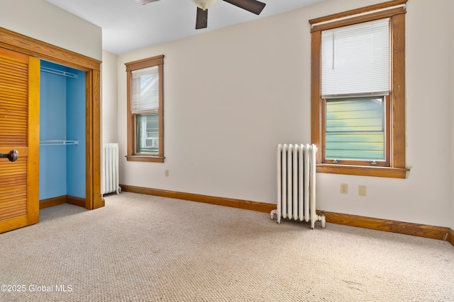 unfurnished bedroom with a ceiling fan, radiator, carpet, and baseboards