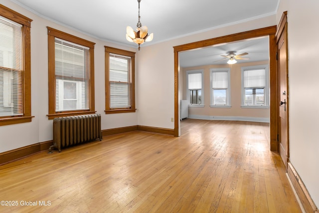 spare room featuring baseboards, ornamental molding, light wood-style flooring, and radiator heating unit