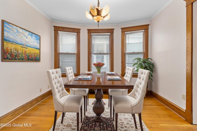 dining area featuring light wood-type flooring, a notable chandelier, crown molding, and a wealth of natural light