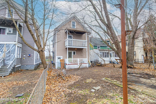 rear view of house with a balcony and fence
