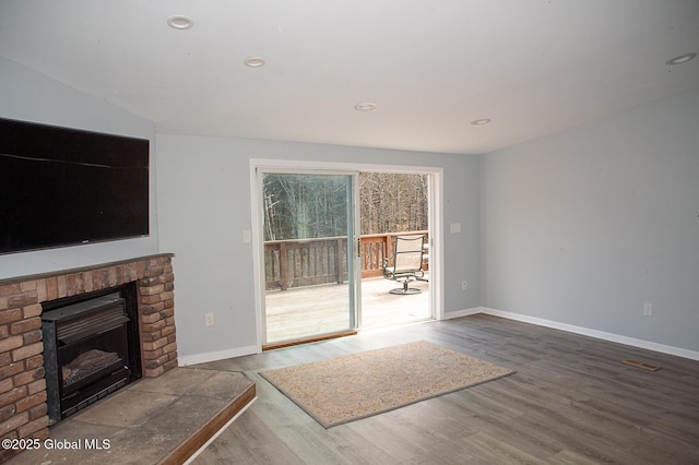 unfurnished living room featuring wood finished floors, baseboards, a brick fireplace, and recessed lighting