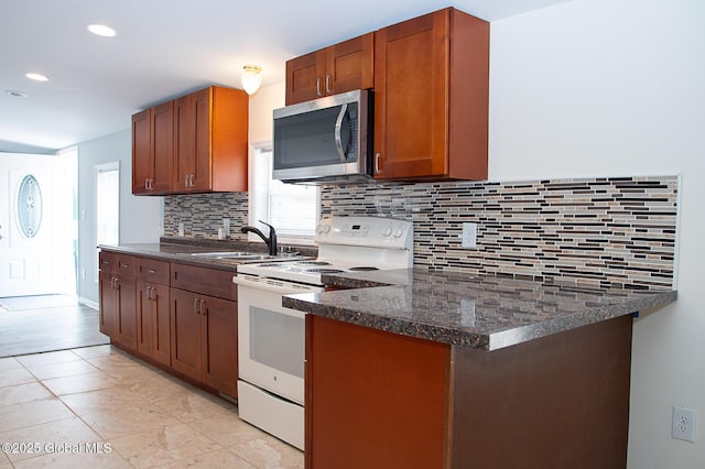 kitchen with a sink, stainless steel microwave, tasteful backsplash, and electric stove