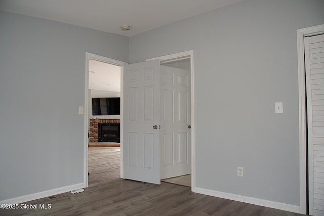 unfurnished bedroom with baseboards, dark wood-style floors, and a fireplace