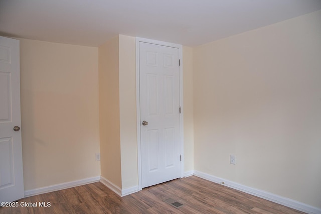 empty room with wood finished floors, baseboards, and visible vents
