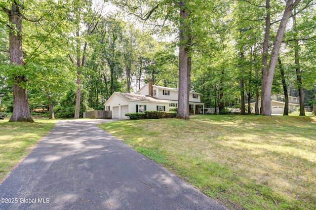 15 Garrison Ln, Clifton Park, NY 12019 - view of front of house with a chimney, asphalt driveway, a front yard, an attached garage, and view of scattered trees